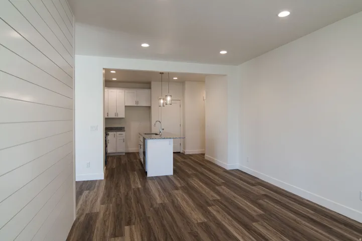 Open-concept living area with wood-finish flooring, recessed lighting, and a shiplap accent wall