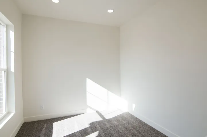 Bright room featuring neutral walls, recessed lighting, a large window, white trim, and plush carpeting