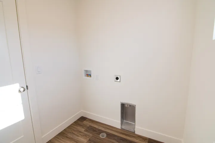 Dedicated laundry area featuring wood-finish flooring and ample wall space