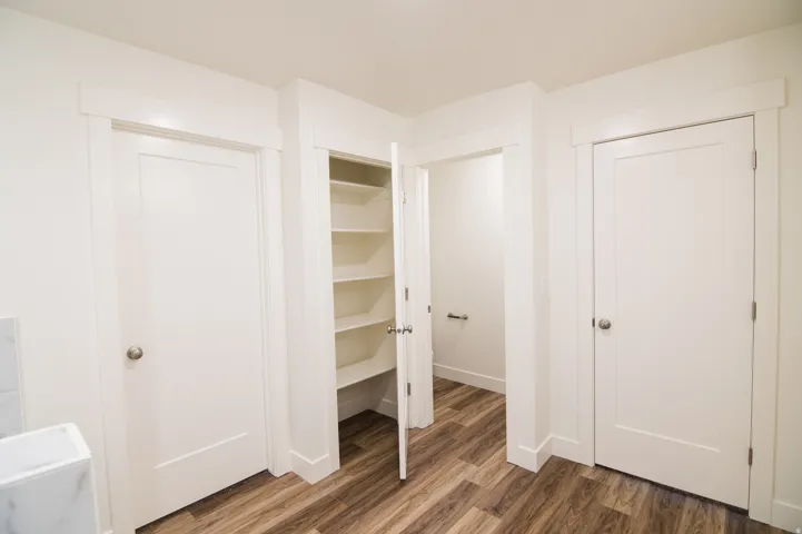 Interior hallway featuring wood-finish flooring, white walls, and bright white trim