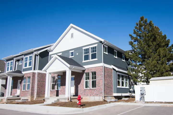 Contemporary townhome featuring a brick and siding exterior, multiple windows, and a covered entryway