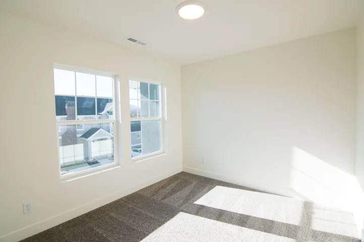 Bright interior space featuring two large windows, neutral-toned walls, and patterned carpeting