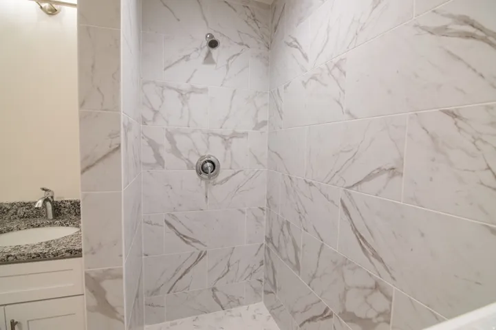 Shower with large format white tile walls featuring gray veining