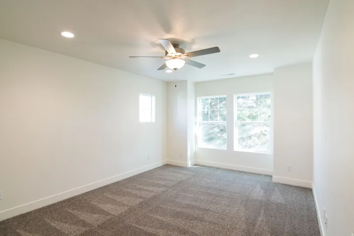 Room featuring carpet flooring, recessed lighting, ceiling fan light fixture, and multiple windows with white trim
