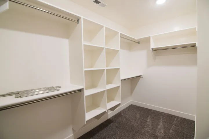 Custom closet system featuring multiple hanging rods, integrated shelving units, and plush carpet flooring