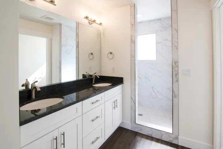 Dual vanity with a dark countertop and undermount sinks, brushed nickel fixtures, and a large wall mirror