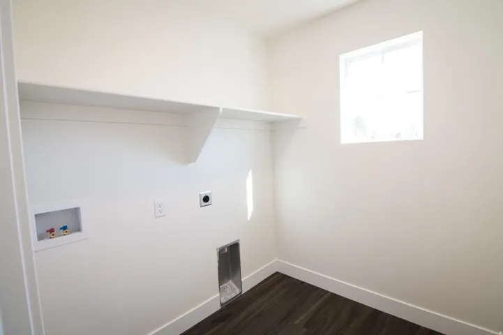 Dedicated laundry area featuring a built-in shelf, wall-mounted electrical outlets, and plumbing connections