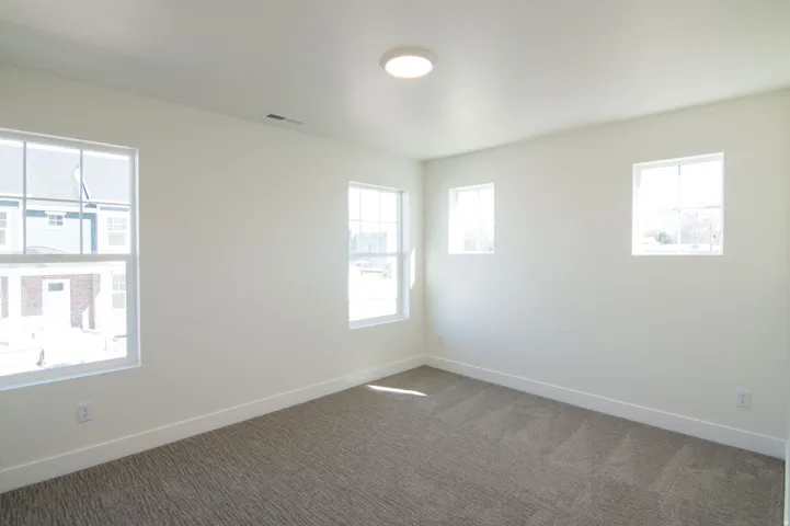 Room featuring neutral-toned walls, textured carpet flooring, and a ceiling-mounted light fixture