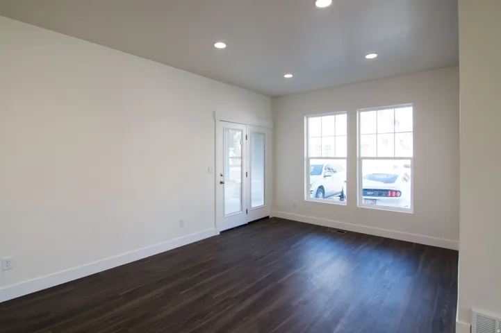 Spacious room featuring dark wood-finish flooring, recessed lighting, and white baseboards
