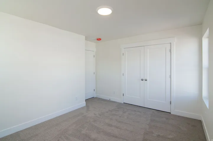 Bright interior space featuring light gray carpet flooring, white walls, and white baseboards