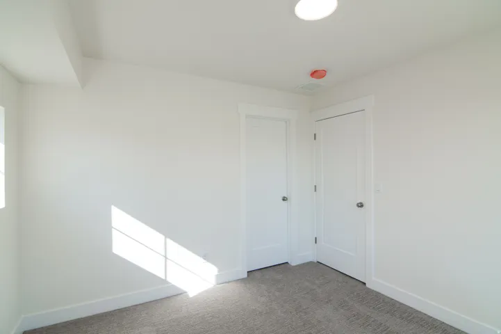 Carpeted room featuring white walls, white trim, two white doors, and a recessed ceiling light