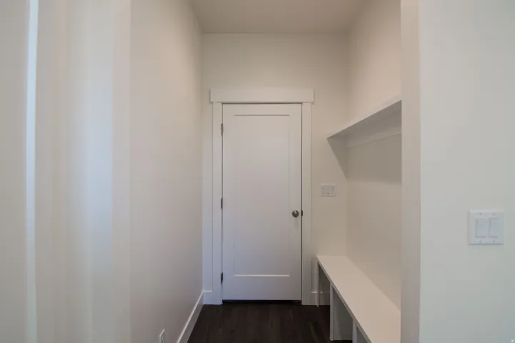 Mudroom featuring wood-finish flooring, built-in bench seating, and an overhead shelf