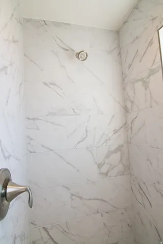 Shower enclosure featuring large format white and gray veined tile