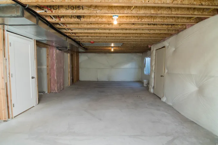 Unfinished basement with concrete flooring, exposed wood joists, and visible HVAC ductwork