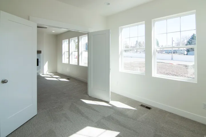 Room featuring three large windows, white trim, light gray carpeting, and a recessed ceiling light