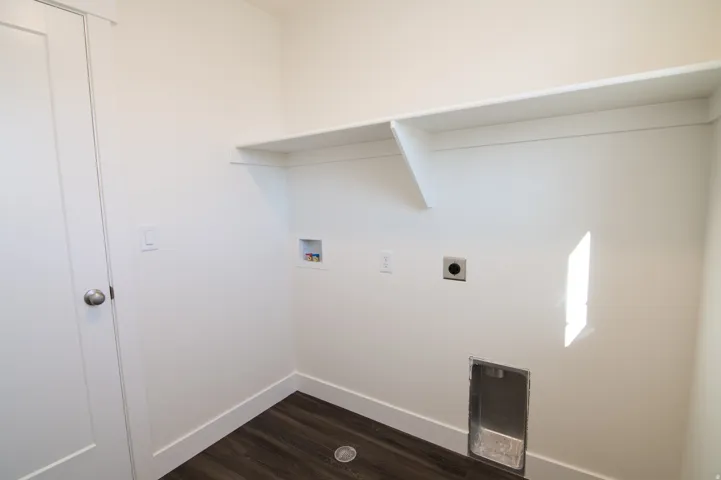Laundry area with wood-finish flooring, white walls, and an integrated shelf for storage