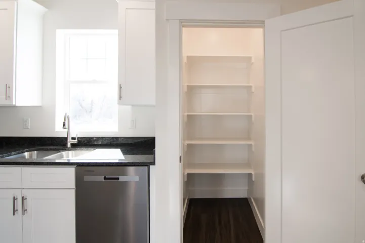 Kitchen pantry with five built-in shelves and wood-finish flooring
