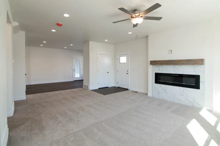 Open-concept living space featuring a modern linear electric fireplace with a wood-finish mantel and marbled tile surround