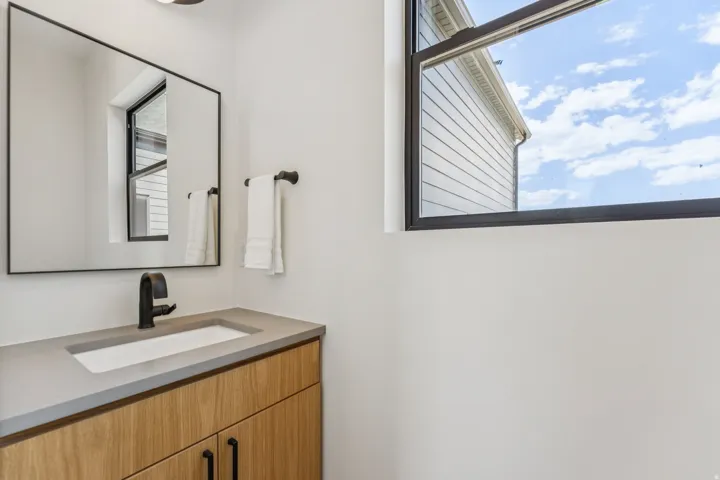 Modern vanity with wood-finish cabinetry, integrated rectangular sink, and matte black faucet