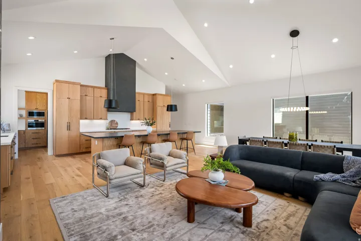 Open-concept living space featuring a vaulted ceiling and wood-finish flooring