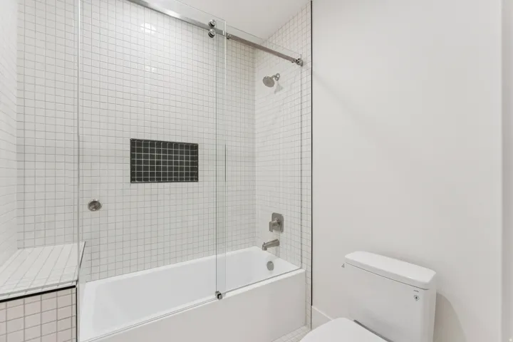 White subway tile bath enclosure with integrated dark tile niche