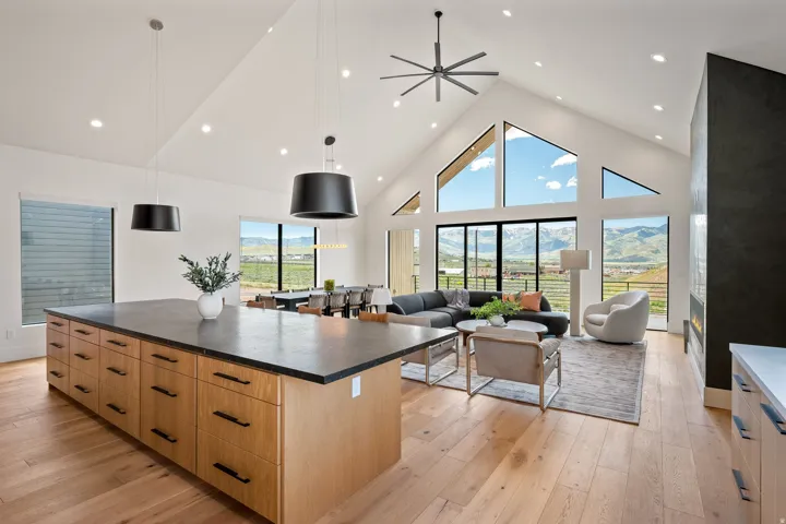 Spacious open-concept interior featuring a vaulted ceiling with exposed beams and a contemporary ceiling fan