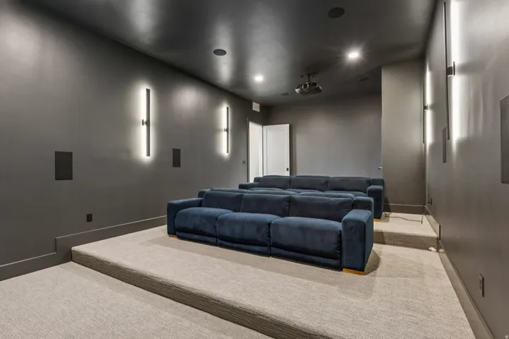 Dedicated media room featuring tiered seating, dark gray walls, and recessed ceiling lighting