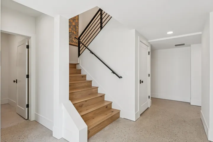 Modern staircase featuring wood treads, a matte black handrail, and horizontal metal balusters