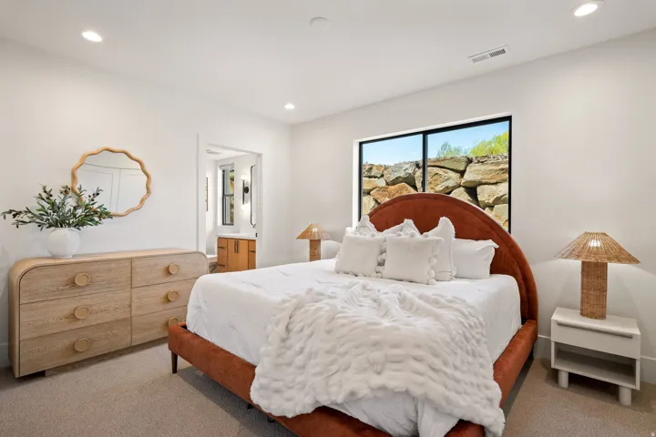 Bright room with recessed lighting, a modern window showcasing a rock wall, and light-toned carpeting