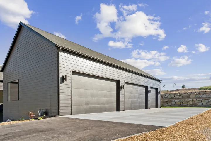 Three-car garage with horizontal siding and a dark shingle roof