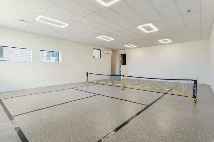 Indoor recreational court featuring a durable speckled flooring, white walls, and multiple rectangular windows