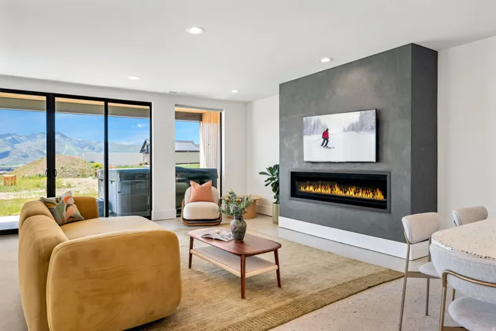 Spacious living area featuring a modern linear fireplace set within a textured accent wall, recessed lighting, and large sliding glass doors opening to outdoor space