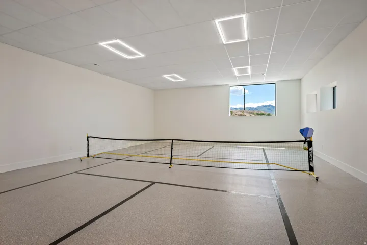 Spacious indoor court featuring a durable speckled floor with court lines, recessed lighting, and a large picture window with a mountain backdrop