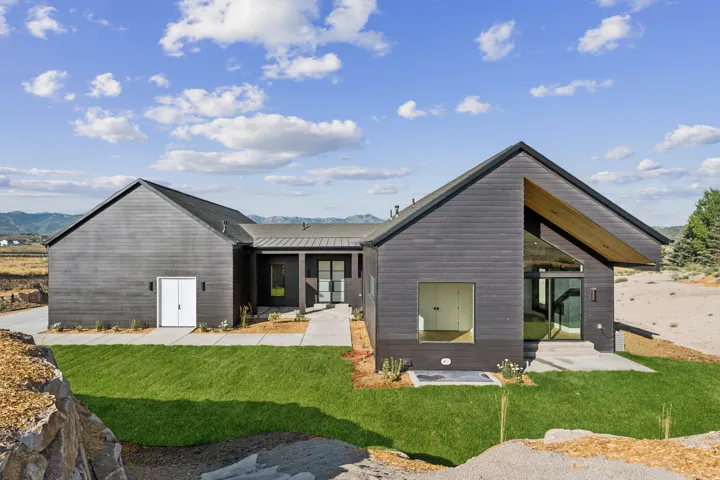 Contemporary exterior with dark horizontal siding, a prominent gabled roofline, and multiple large windows