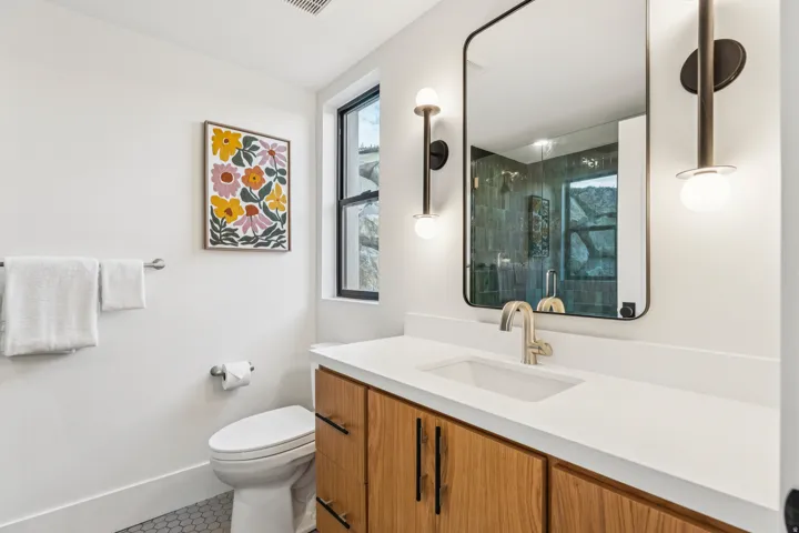 Contemporary bathroom featuring a wood-finish vanity with a white countertop and integrated sink