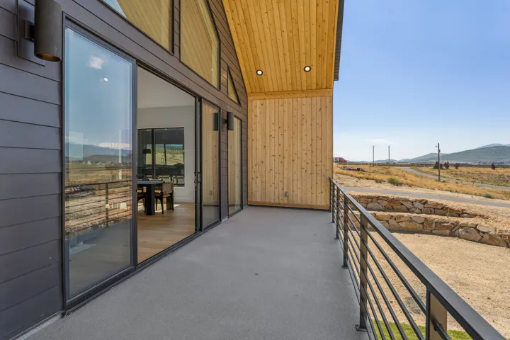 Expansive outdoor balcony featuring a concrete surface, black metal railings, and dual exterior sconces