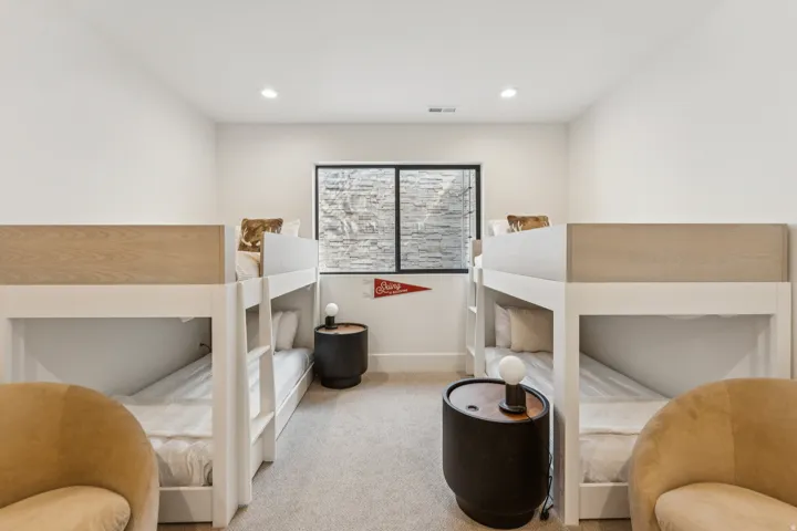 Room featuring two built-in bunk beds with wood-finish accents, recessed lighting, and a window with a stone-textured exterior