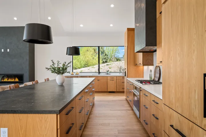Contemporary kitchen featuring light wood cabinetry and a large center island with a dark countertop