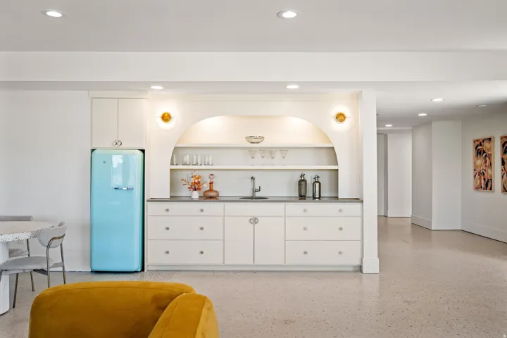 Built-in wet bar featuring white cabinetry, an integrated sink, and dark countertops