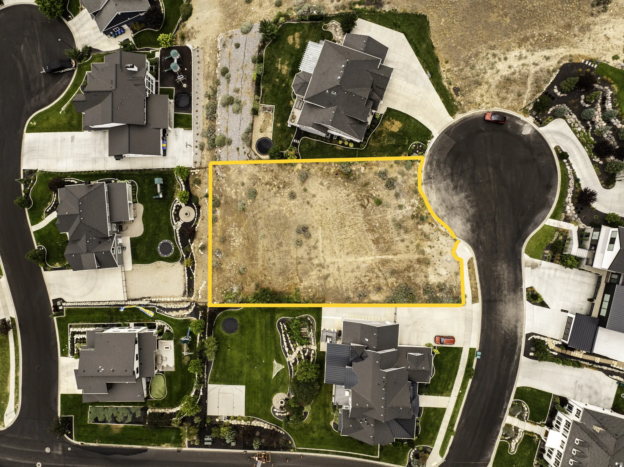 Vacant land parcel featuring a level topography, surrounded by established residences, and bordered by paved roadways