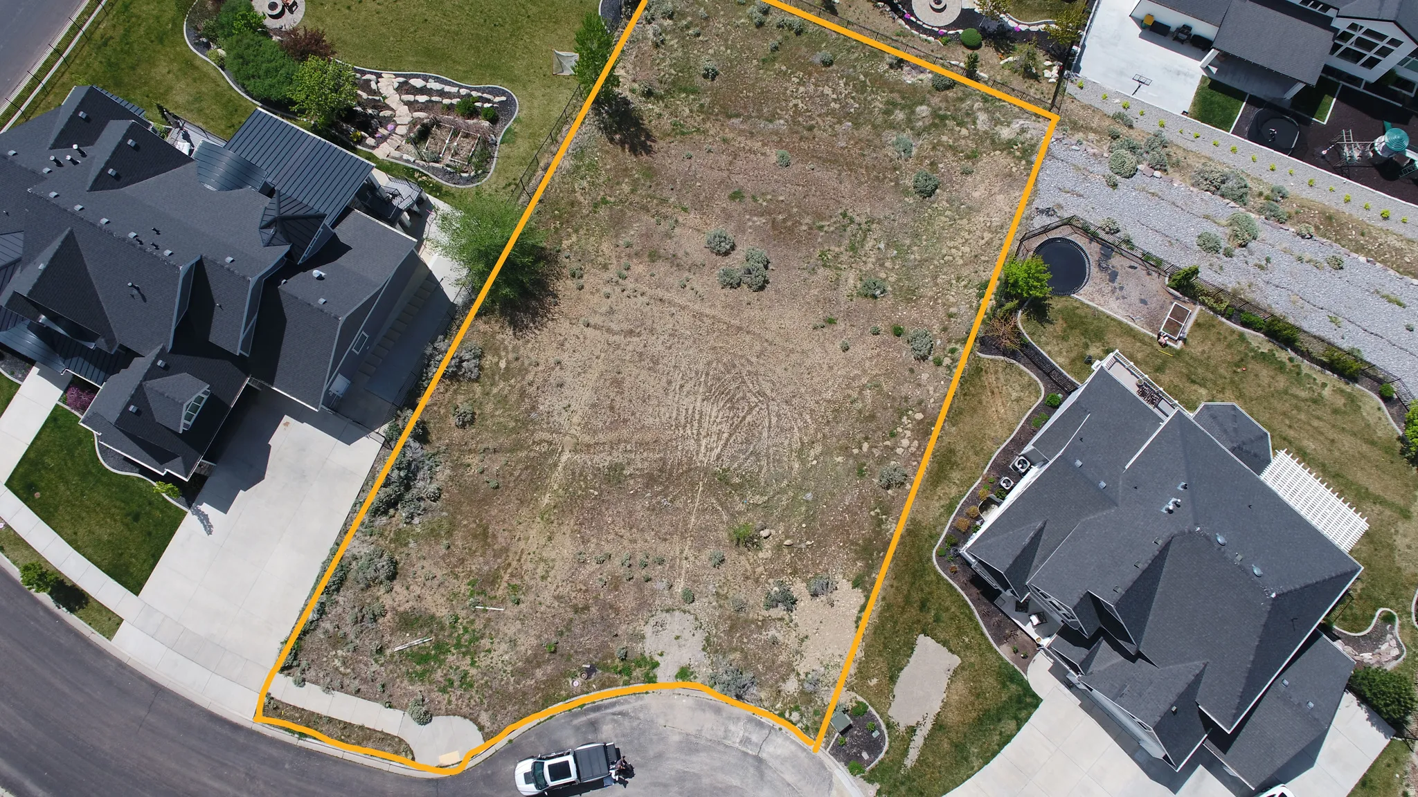 Aerial view of lot bordered by established residences and paved street