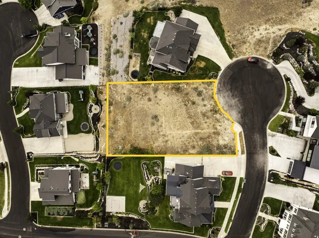 Vacant land parcel featuring a level topography, surrounded by established residences, and bordered by paved roadways