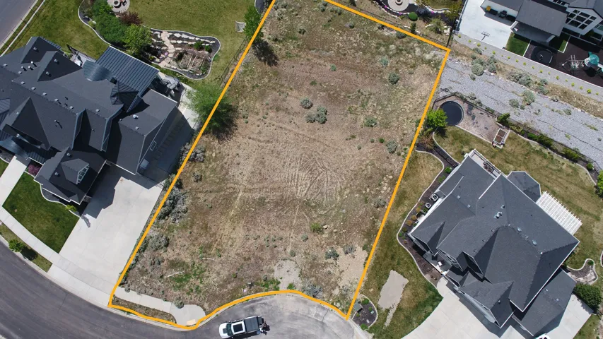 Aerial view of lot bordered by established residences and paved street