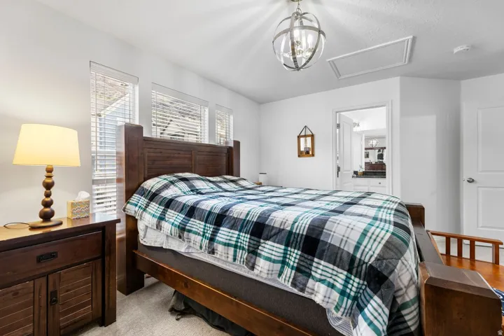 Bedroom featuring multiple windows with blinds, a prominent ceiling-mounted light fixture, and an entry door