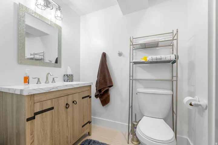 Bathroom featuring a wood-finish vanity with a white countertop, an undermount sink, and a framed mirror