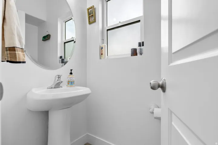Pedestal sink with chrome faucet, complemented by an oval wall-mounted mirror
