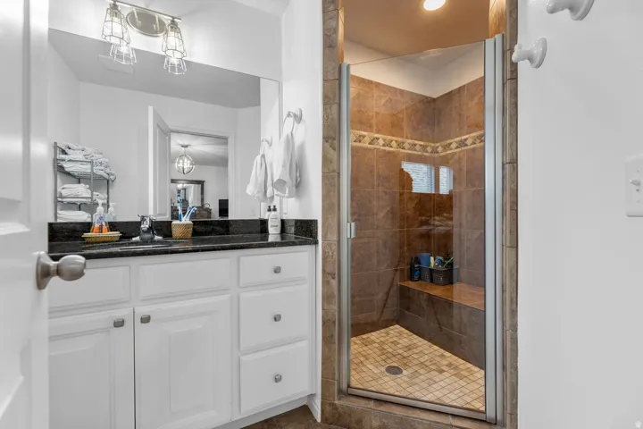 Frameless glass shower enclosure with floor-to-ceiling tile, featuring an integrated bench