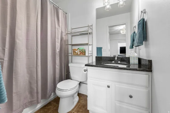 Bathroom featuring a white vanity with a dark countertop, an undermount sink, and a wall-mounted mirror