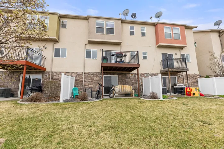 Townhome exteriors featuring multiple balconies, ground-level patios, and a stone facade