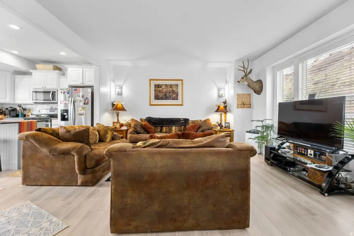 Open-concept living area featuring light wood-finish flooring, white walls, and recessed lighting